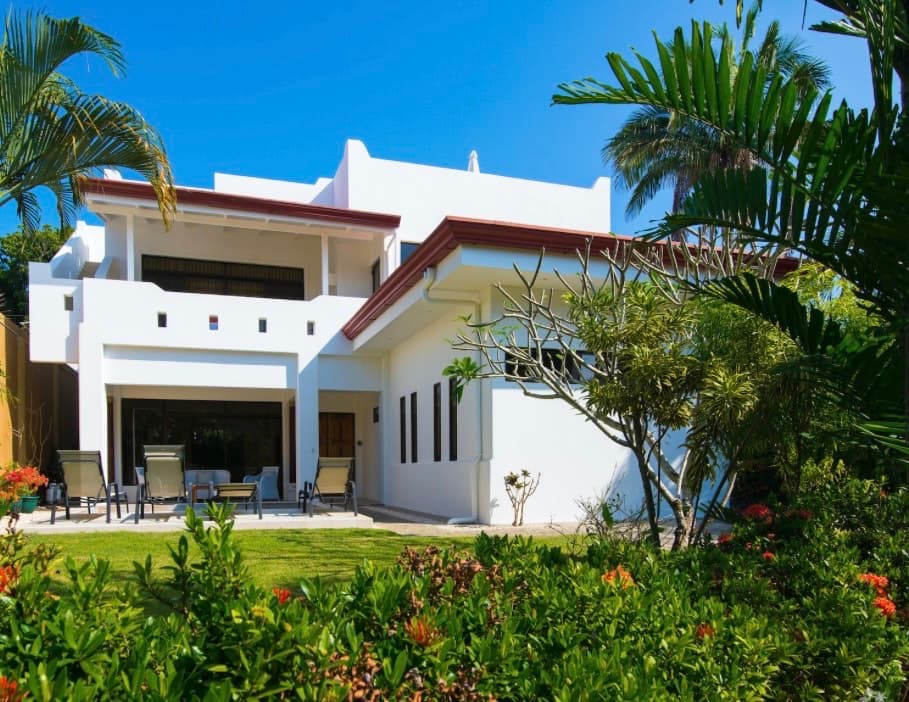 Hermosa Palms white villa with tropical landscaping and palm trees in Jaco Beach