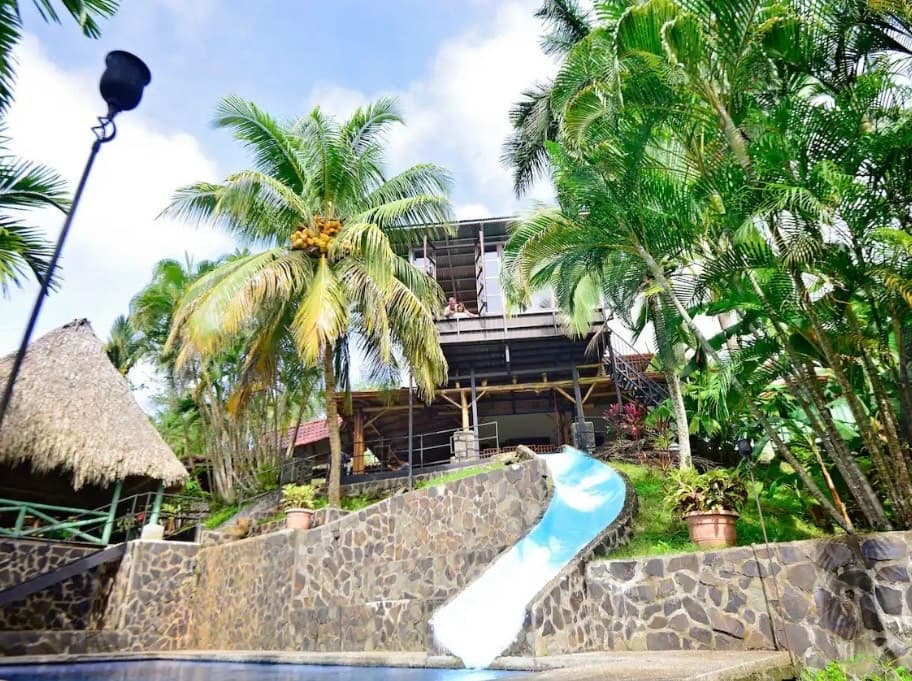 Jungleland tropical paradise with blue waterslide pool, palapa, and lush palm trees in Jaco Beach