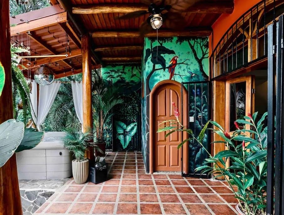 Villa Mariposa jungle-inspired tropical beach house entrance with macaw wall mural and hot tub